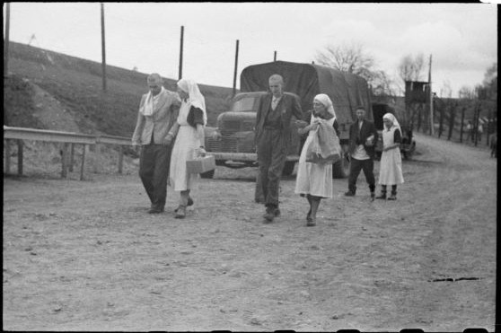 Des déportés du camp de Vaihingen libéré sont soutenus par des infirmières jusqu'aux tentes sous lesquelles un bataillon médical va leur prodiguer les premiers soins.