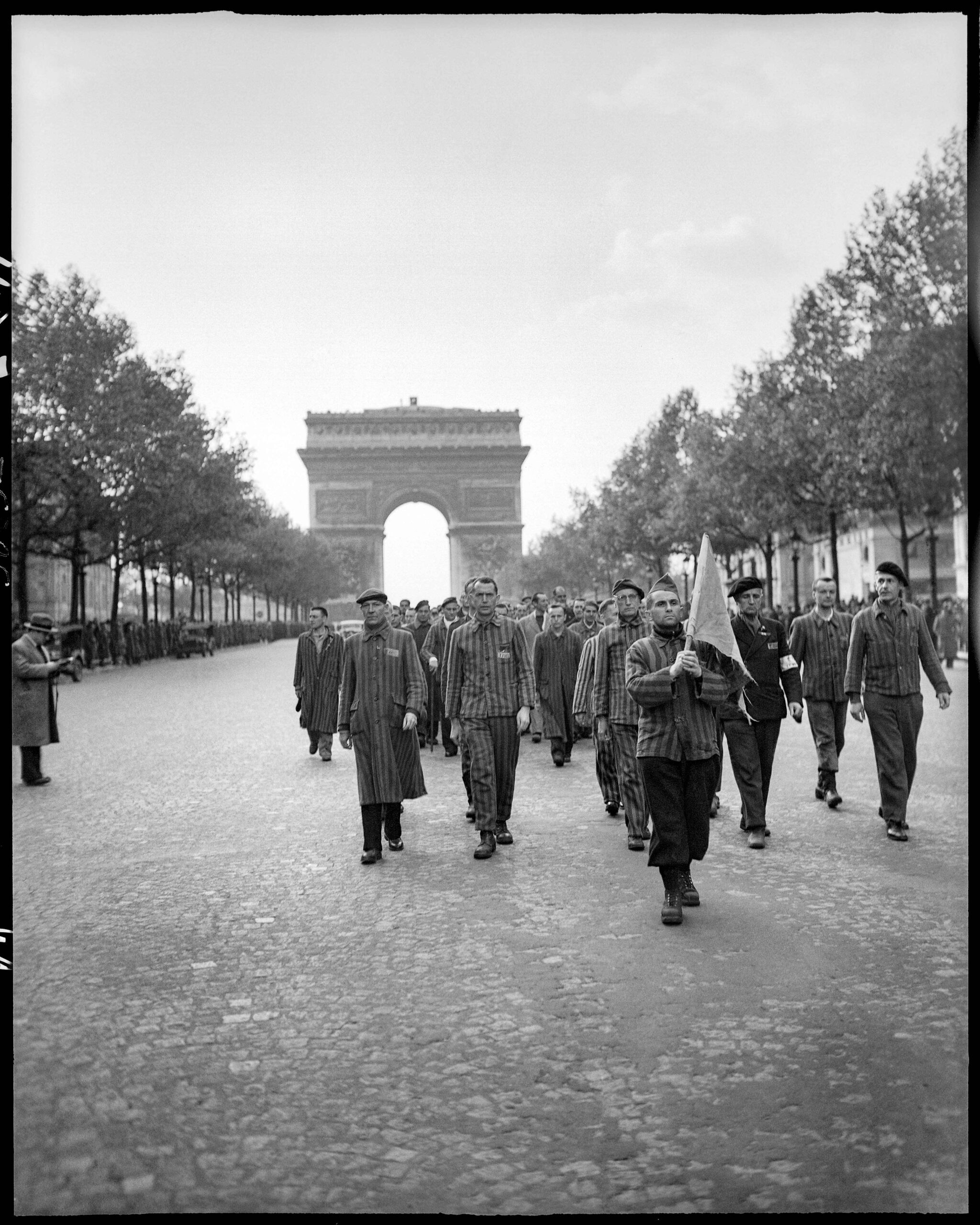 Des rescapés des camps remontent les Champs-Élysées avant de raviver la flamme de l’Arc de Triomphe avec le général Koenig
